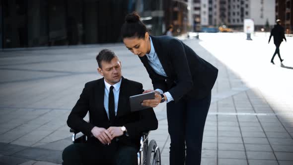 Invalid Boss Businessman in Wheelchair an His Lady Secretary Work with Digital Pad