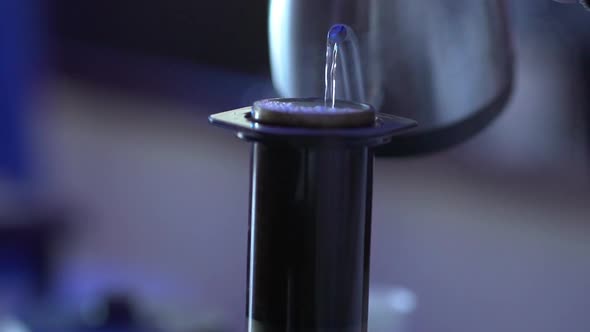 Closeup Shoot of Person Pouring Boiling Water From Metal Kettle Into Aeropress to the Brim for