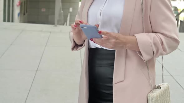 Elegant Businesswoman Typing a Text Letter on a Mobile Phone Using the Internet