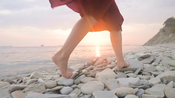 Close-up Slow Motion Following Behind the Legs of a Barefoot Girl in a Red Dress Fluttering in the