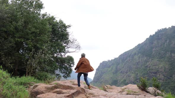 Young man running up a mountain then stop at a cliff.