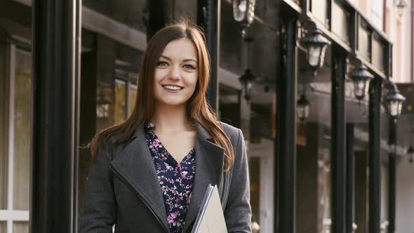 Portrait of Young Beautiful Young Businesswoman Looking at Camera with Smile Outdoors, in the Hands