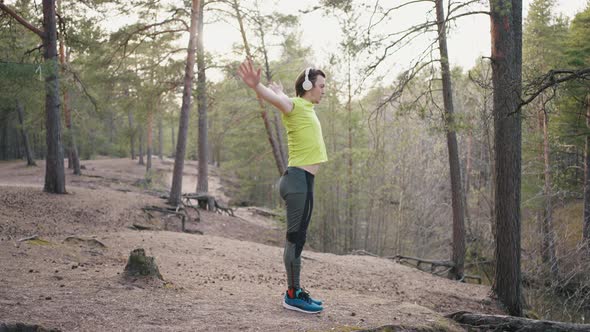 Young Male Runner Warms Up Before Jogging in Pine Forest