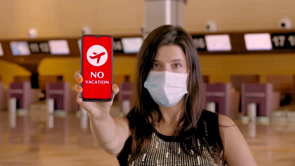 Woman, in Protective Mask, Holds Smartphone with COVID-19 Icon, Text, No Vacation, on Screen