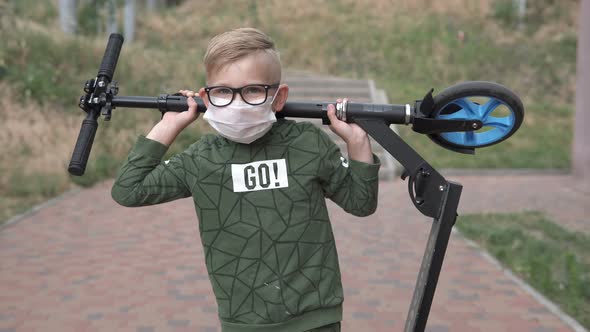 A boy carries a scooter over his head on the street during quarantine.