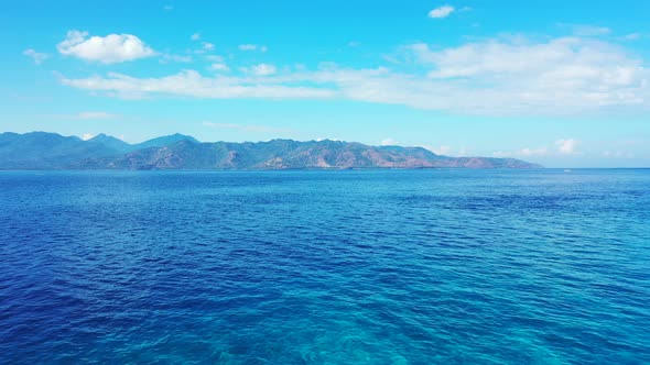 The Beautiful And Calm Blue Waters Of Indonesia With Mountains, Sky And Clouds In Background - Aeria