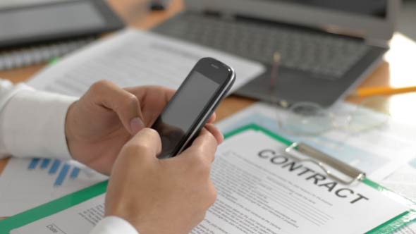 Businessman Typing on Smartphone in Office