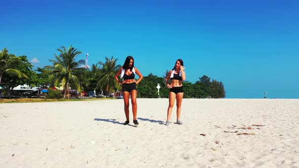 Young beauty models relaxing by the sea on the beach on clean white sand and blue background 