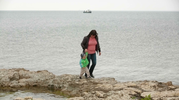 Mother And Baby Walking At The Seaside In Autumn alt