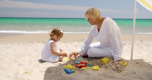 Cute Girl And Grandmother Playing On The Beach