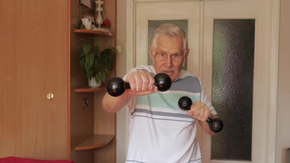 Senior Elderly Caucasian Man Doing Sports Exercises with Dumbbells at Home