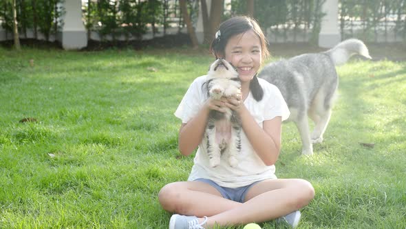 Happy Asian Children Playing With Siberian Husky Dog In The Garden