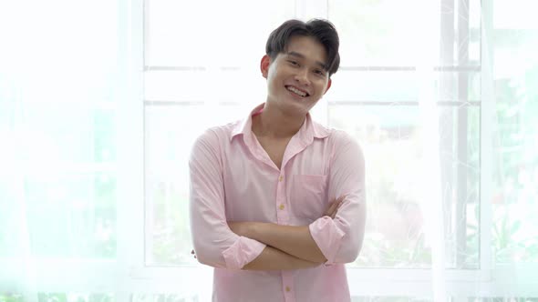 Portrait of asian young gay smiling with arms crossed look at camera in the room at home, LGBT