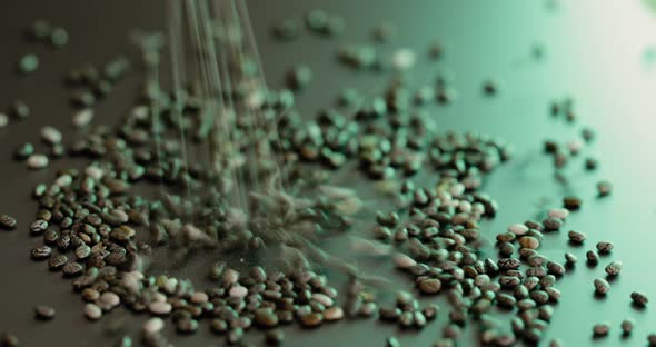 Closeup of Small Chia Seeds Falling on a Gray Table in Green Light