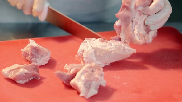 Closeup of Female Hands Cutting Pieces of Meat