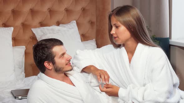 Beautiful Couple Relaxing Together in Bed, Wearing Bathrobes