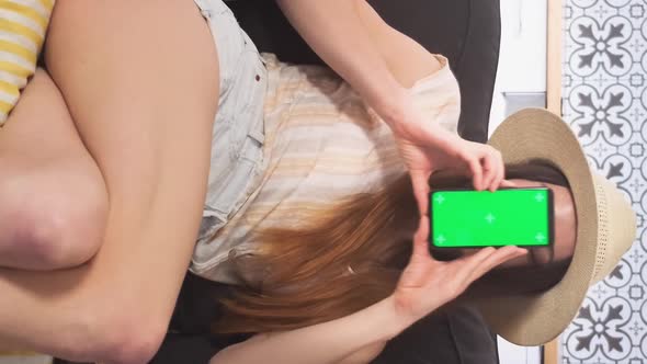 Vertical Footage Happy Woman with Green Phone Screen Rejoices Cheap Flying Air Tickets