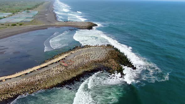 Ocean waves crashing on the breakwater pier, Glagah Beach, Indonesia, aerial