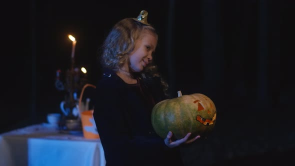 Cute Girl with Halloween Jackolantern Standing in Darkness Smiling Looking Away