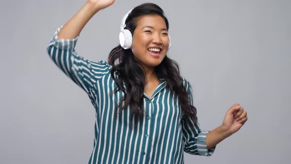 Asian Woman in Headphones Listening To Music