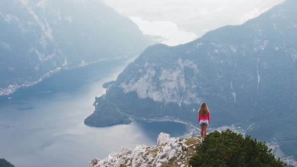 Young Woman Standing on Mountain Top and Contemplating Beautiful View of Mountain Lake