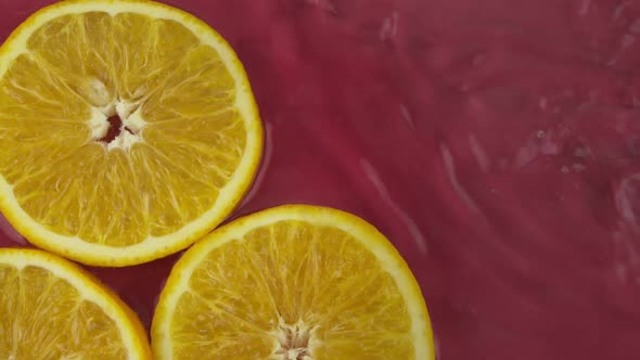 Juicy Orange Pieces of Fresh Oranges in Clean Water Splash on Red Background
