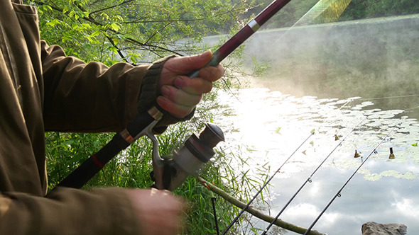 Fisherman Pulls The Fishing Line On Reel