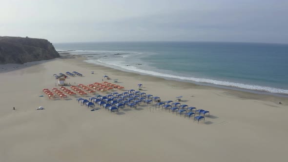 Aerial view of a empty beach filled with blue and red beach tents 