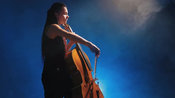 Young Beautiful Woman Playing a Melody on Cello. Smoky Dark Studio