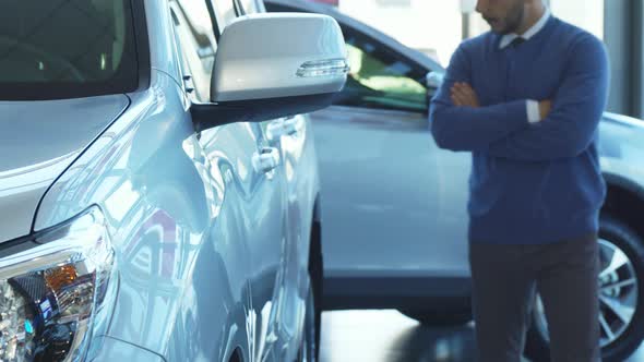 A Solid Man Walks Through the Automobile Showroom and Looks at the Car