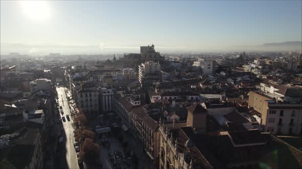 Cathedral of Granada with sun shining in sky and downtown, Spain. Aerial forward ascending