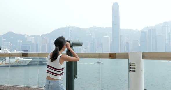 Woman tourist looking though binocular in Hong Kong  