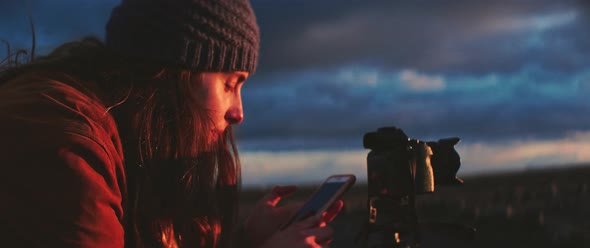 Person uses phone to adjust camera setting during sunset