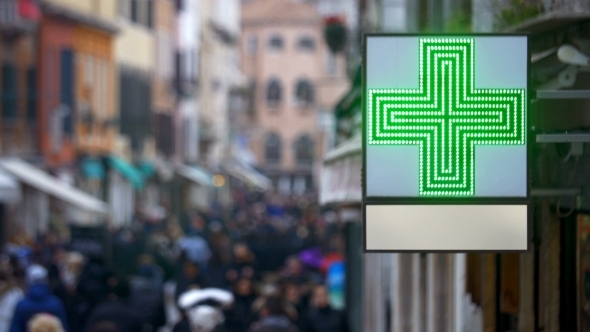 Pharmacy Sign With Green Cross In Busy Street
