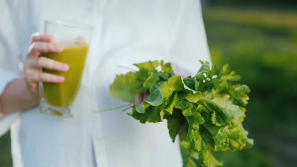 The Girl Holds a Glass of Green Cocktail and Lettuce. Healthy Eating Concept