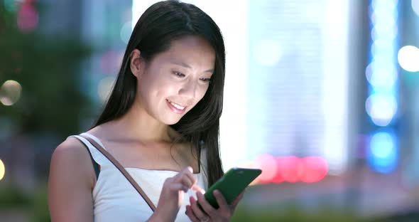 Young woman use of mobile phone in the city at night