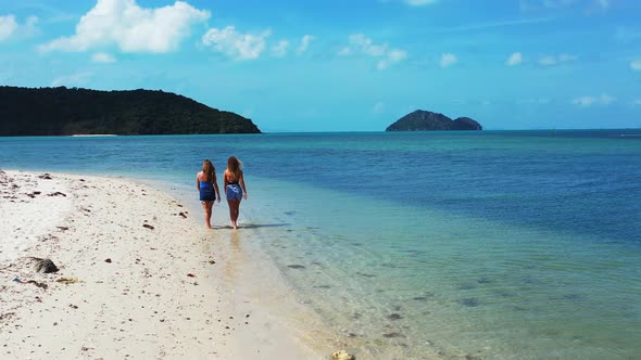 Young smiling ladies relaxing having fun on beach on paradise white sand and blue 