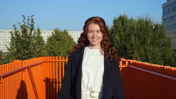 Young Woman in White Clothes with Jacket Walks Along Bridge