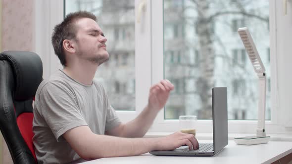 A young guy is tired of working, he is wearing a gray t-shirt