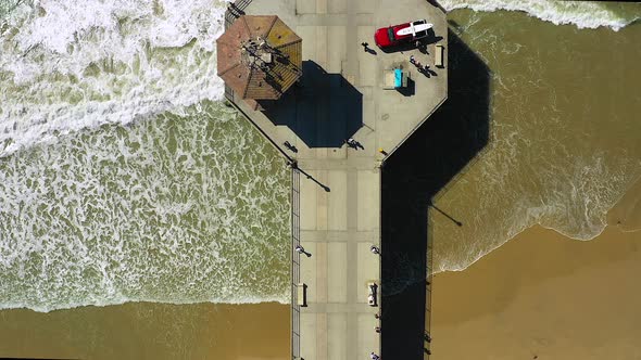 Drone footage of people walking on a pier, at the ocean, taken from a drone