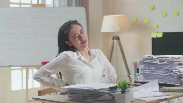 Asian Woman Having Backache While Working Hard With Documents At The Office