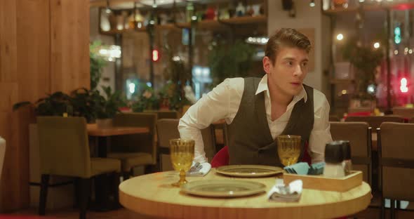 Handsome Young Man is Sitting in a Restaurant Awaiting