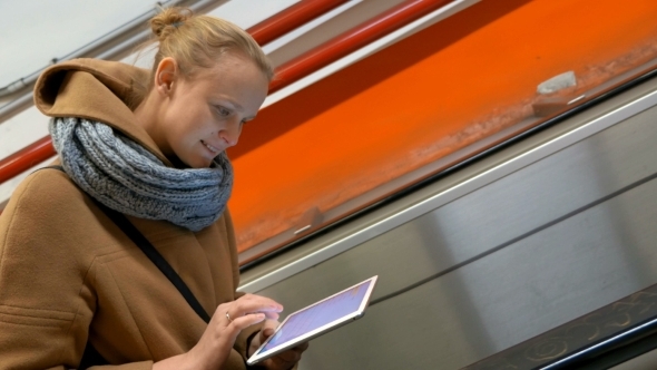 Woman On Escalator Using Tablet Computer alt