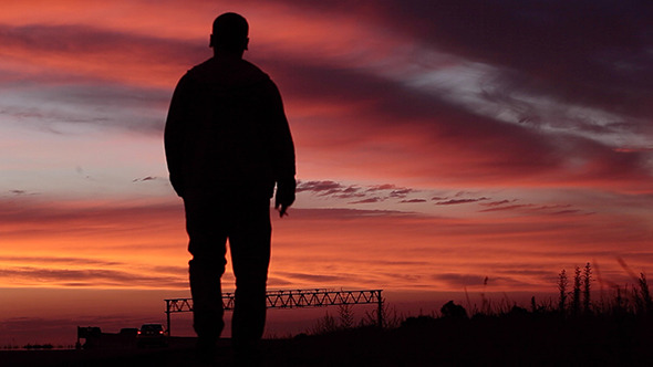 Lonely Man Goes Along The Road Against Sunset