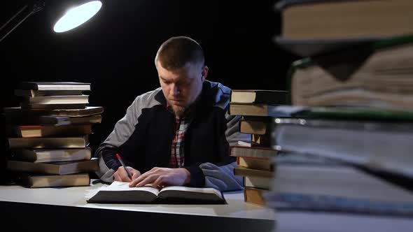 Man Reading a Book and Writes in a Notebook. Black Background