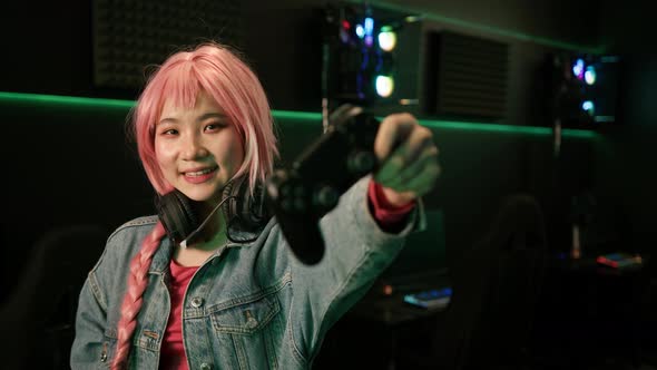 Indoor Shot in a Dark Room of a Cute Pretty Asian Girl with Long Pink Braid Wearinga Denim Jacket