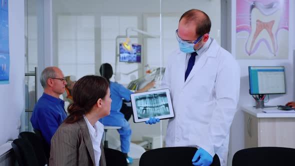 Stomatologist Pointing on Digital Screen Explaining Xray to Woman