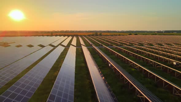 Aerial drone view into large solar panels at a solar farm at bright sunset. HDR footage