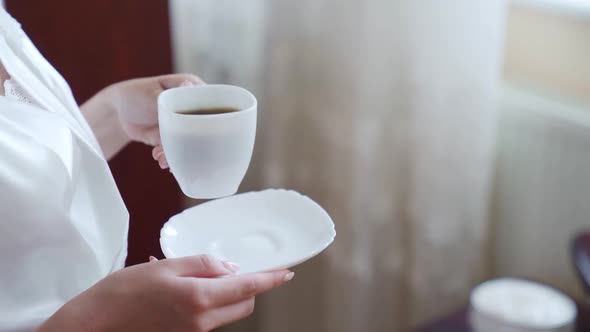 Closeup shot of a woman walking to the balcony with a cup of coffee. Slow motion