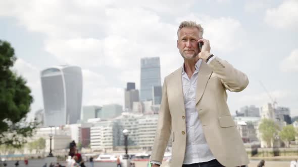 Businessman having phone call, London skyline in background